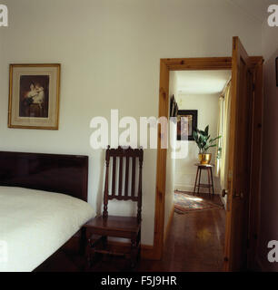Antique wooden chair bed and doorway in a small eighties cottage bedroom Stock Photo