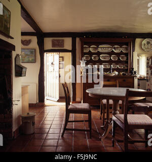Quarry tiled flooring in an eighties cottage dining room with an antique pine dresser and vintage wooden table and chairs Stock Photo