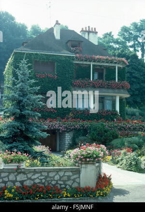 Exterior of a French country house with profusely flowering geraniums in window boxes on the balconies Stock Photo