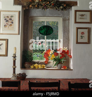 Vase of tulips on window with stone lintel in cottage dining room Stock Photo