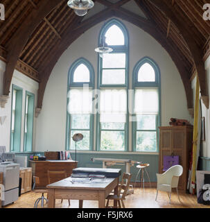 White blinds on tall Gothic style windows in a large studio dining room in a converted chapel Stock Photo