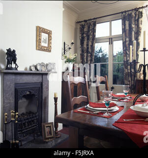 Dark wood table set for lunch in nineties dining room with a black marble fireplace Stock Photo