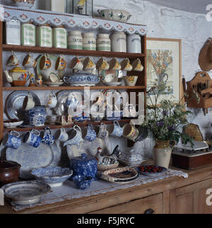 Collection of vintage ceramic storage jars and blue+white china on old pine shelves in  a cottage kitchen Stock Photo