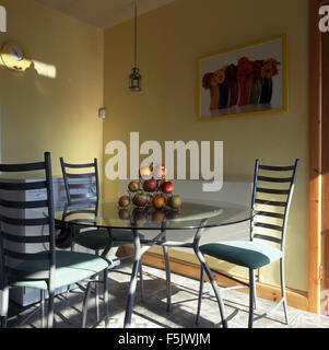 Metal ladder back chairs and circular glass topped table in a  nineties dining room Stock Photo