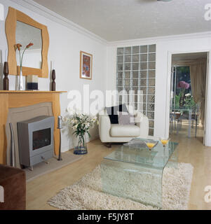 Acrylic coffee table on shag pile rug in a nineties living room with a metal gas fire and a glass brick wall beside doorway Stock Photo