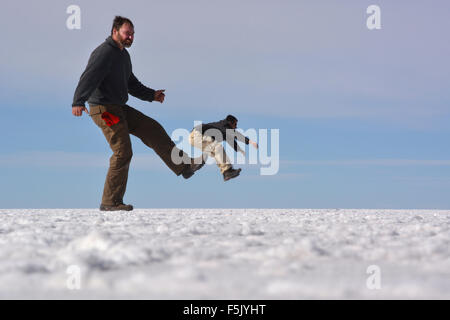 Optical illusion, man being kicked, Salar de Uyuni, Bolivia Stock Photo