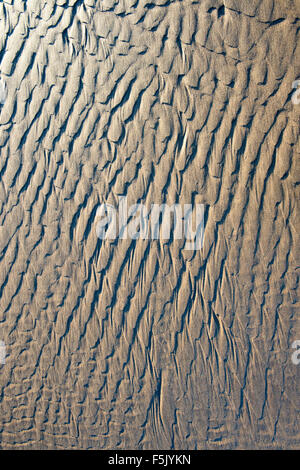 Water patterns on sand with shadows and morning light Stock Photo