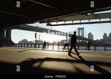 Two Chinatown women exercise, a man runs,  another man walks while watching the others along the East River Esplanade, New York Stock Photo