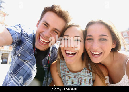 Group of happy teen friends laughing and taking a selfie in the street Stock Photo