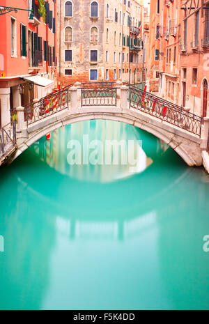 Bridge on Water Canal Venice in a long exposure photography. Venetian small bridge and buildings in its typical architecture. Stock Photo