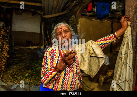 Elderly woman smoking a cigarette while talking in her home Stock Photo