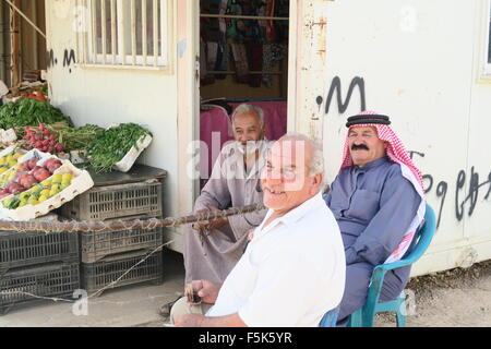 Three men from Syria and Afghanistan relax outside a fruit and vegetable shop at Zaatari refugee camp in Jordan Stock Photo