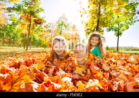 Kids having fun laying on the ground with leaves Stock Photo