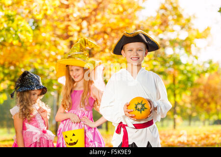 Friends in Halloween costumes hold small pumpkin Stock Photo