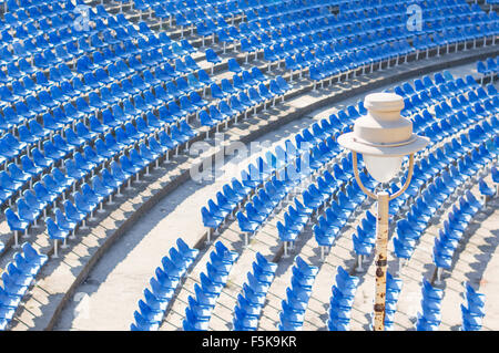 Light bulb in an empty amphitheater with blue chairs hall on daytime Stock Photo