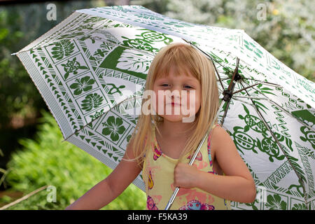 Little girl in the country holding an umbrella. Stock Photo