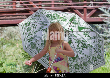 Little girl in the country holding an umbrella. Stock Photo