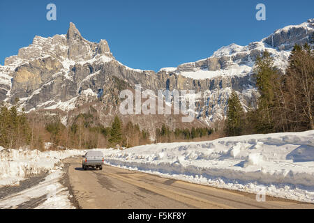 a pick up truck driving on a snowy road leading to a mountain Stock Photo