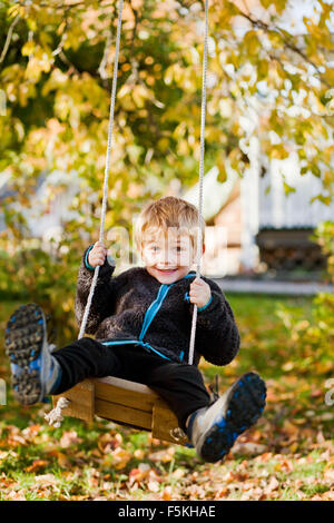 Sweden, Sodermanland, Strangnas, Boy (4-5) playing on swing in garden Stock Photo