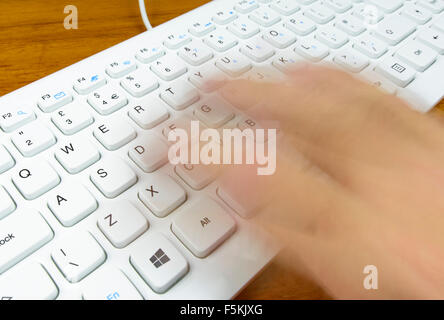 Typing fast on a computer keyboard, with the typists hand blurred to infer speed. Stock Photo