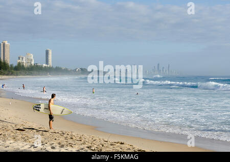 Surfers at Burleigh Heads, Tower block apartments at Surfers Paradise in distance, Queensland, Australia Stock Photo