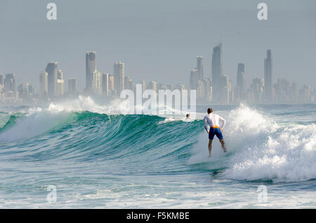 Surfers at Burleigh Heads, Tower block apartments at Surfers Paradise in distance, Queensland, Australia Stock Photo