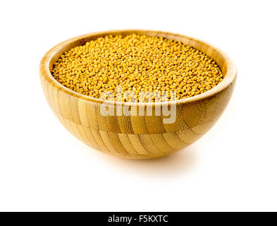 Isolated shot of yellow mustard seeds spice in traditional bowl against white background. Stock Photo