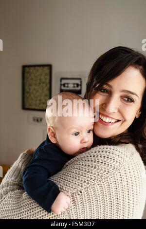 Mother holding baby son, looking over shoulder Stock Photo