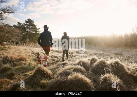 Rear view of mother and son running on grassland Stock Photo