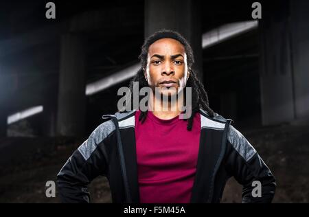 Portrait of male boxer with hands on hips standing below urban flyover Stock Photo