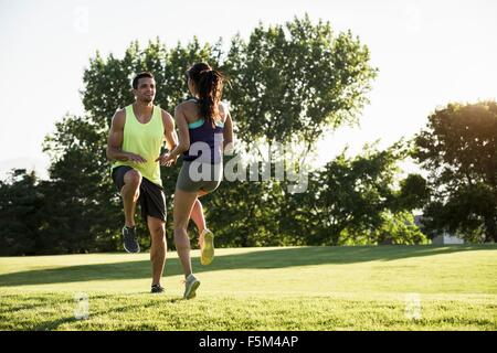 Young man and woman doing running on spot training in park