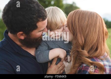 Mother and father holding young son, outdoors