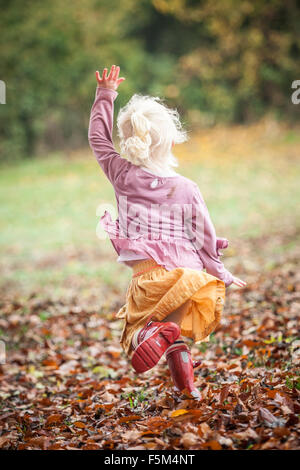 Three-year-old girl playing in a leafy autumn park. Stock Photo