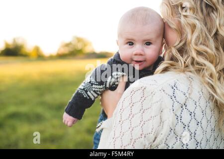 Portrait of baby boy in mothers arms in field Stock Photo