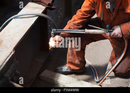 Welder lighting welding flame in shipyard workshop Stock Photo