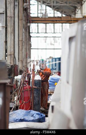 Welder checking gas cylinder in shipyard workshop Stock Photo