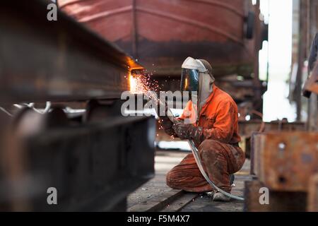 Welder welding girder in shipyard workshop Stock Photo