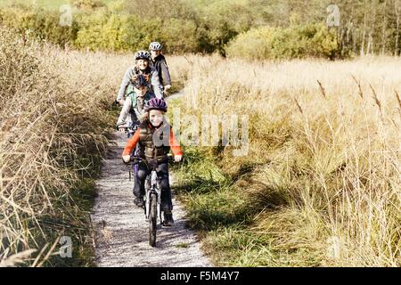 Front view of family cycling on rural path looking at camera smiling