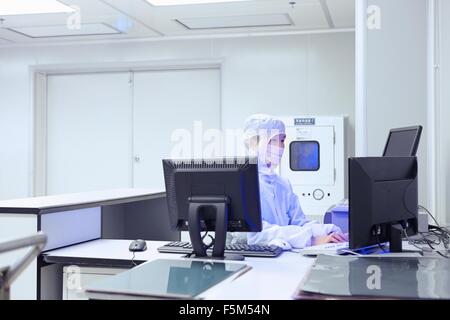 Female factory worker using computer in flexible electronics factory clean room Stock Photo