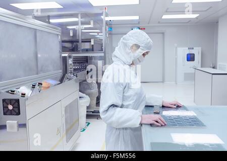 Female worker inspecting flex circuit in flexible electronics factory clean room Stock Photo
