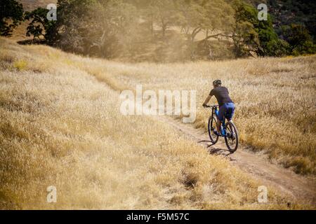 Elevated rear view of young man mountain biking on dirt track, Mount Diablo, Bay Area, California, USA Stock Photo