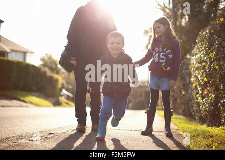 Mother and two children walking along country road Stock Photo