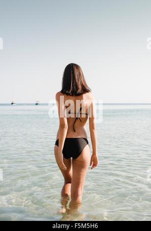 Rear view of young woman wearing bikini paddling in sea Stock Photo