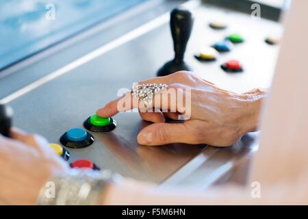 Close up of senior womans hand pressing button on games machine Stock Photo