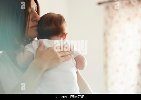 Mother carrying baby in bedroom Stock Photo