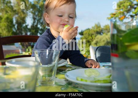 Female toddler eating at table outdoors Stock Photo