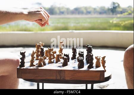 Cropped shot of woman and man playing chess at safari lodge, Kafue National Park, Zambia Stock Photo