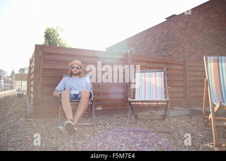 Young man alone on deckchair at rooftop party