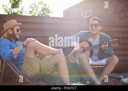 Two male friends playing guitar at rooftop party Stock Photo