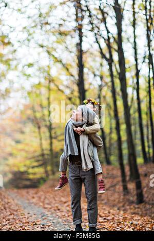 Mother giving daughter piggyback ride in autumn forest Stock Photo